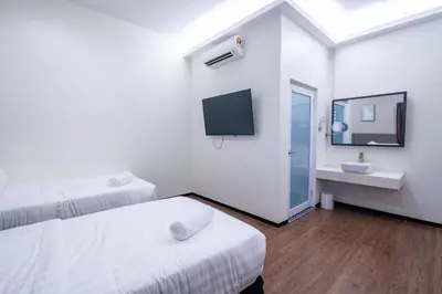 a room with two beds and a sink and a tv at King's Lane Ipoh in Ipoh