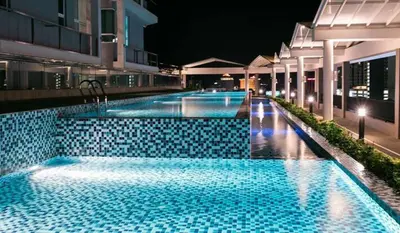 a swimming pool at night with blue tiles at H2H - Octagon Cottage at Ipoh Town Center in Ipoh