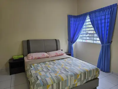 a bedroom with a bed with blue curtains and a window at The Simplicity Homestay in Tanah Rata