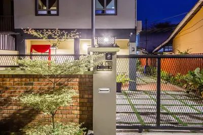 a house with a brick wall and a fence at Explore 4BR Gardenhouse Retreats (Free Parking) in Butterworth