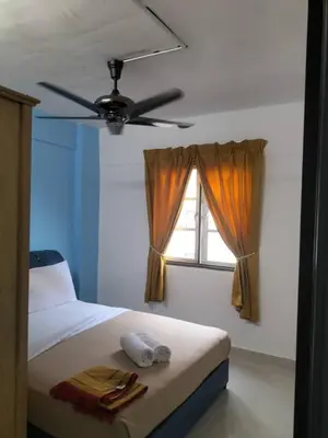 a bedroom with a bed with a ceiling fan and a window at Homestay pangsapuri sutera seberang jaya in Kampong Telok