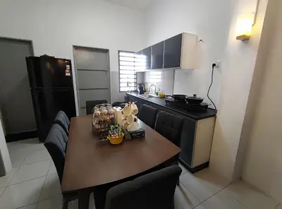 a kitchen with a wooden table and a kitchen with a black refrigerator at HOMESTAY SYAABAN Kamunting Taiping Batu Kurau Ulu Sepetang in Kamunting