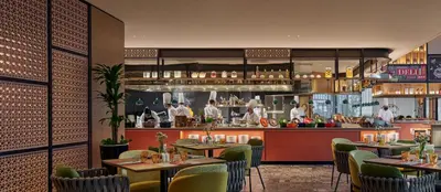a restaurant with tables and chefs in the kitchen at Amari SPICE Penang in Bayan Lepas
