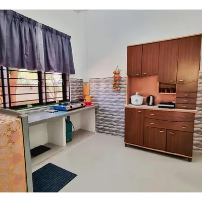 a kitchen with wooden cabinets and a counter top at HomeStay with Serene Surrounding in Nibung Tebal