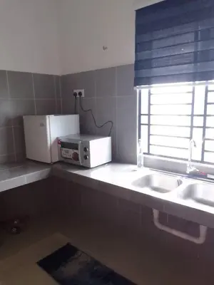 a kitchen with a microwave and a sink and a window at HOMESTAY IMPIAN, BATU GAJAH PERAK in Kampong Paya Rengas