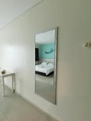 a mirror on a wall in a room with a bed at Peaceful 1-bedroom unit at Marina Island by JoMy Homestay in Lumut