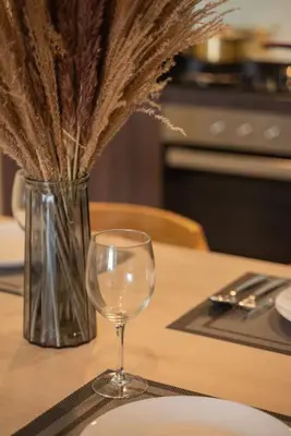 a table with a wine glass and a vase with dry grass at Deluxe Seaview Suite Twin Bed by The Only Bnb in Tanjong Tokong