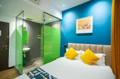 a bedroom with a blue wall and a bed with yellow pillows at Apollo Inn in George Town