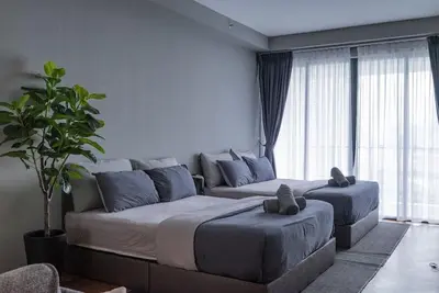 a bedroom with two beds and a couch and a plant at Deluxe Seaview Suite Twin Bed by The Only Bnb in Tanjong Tokong