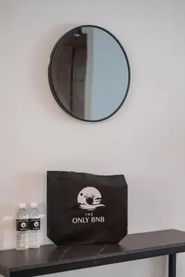 a mirror on a wall next to a table with a bag at Deluxe Seaview Suite Twin Bed by The Only Bnb in Tanjong Tokong
