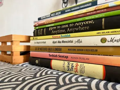 a stack of books sitting on a bed at Solehah Homestay in Seri Iskandar