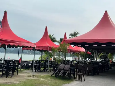 a group of tables and chairs with red umbrellas at Omari Marina Island Homestay Lumut in Lumut