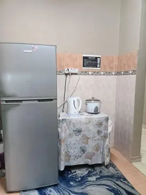 a kitchen with a refrigerator and a table with a tableablishthritisthritisthritisthritis at Homestay Wafiy Lost World Tambun Ipoh in Ipoh