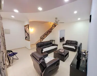 a living room with leather furniture and a staircase at JackBeansprouts Homestay Botani Ipoh in Ipoh