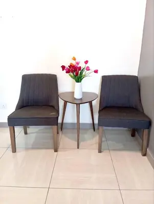 two chairs and a table with a vase of flowers at Octagon Premium Ipoh Town Center 2BR 101 by Grab A Stay in Ipoh