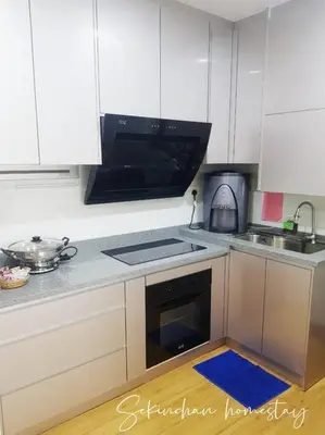 a kitchen with white cabinets and a blue rug on the floor at Best Sekinchan homestay in Sekincan