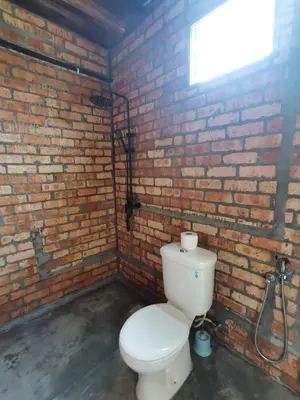 a bathroom with a toilet and a brick wall at Sayang Di Kaki Bukit Homestay Near Icon City Bukit Mertajam in Bukit Mertajam