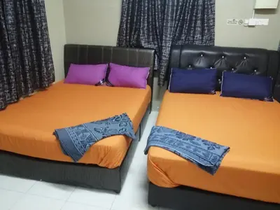 two beds with orange and purple pillows in a room at Kamar Musafir MMS in Ipoh