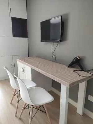 a desk with two chairs and a television on a wall at Kampar Bonvoy Champs Elysees 4pax Homestay in Kampar