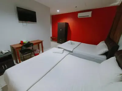 a bedroom with two white beds and a red wall at Reintree Lodge Hotel in Ipoh