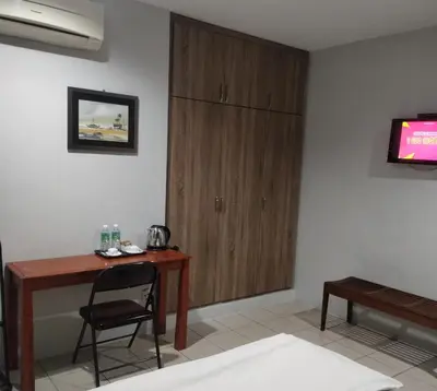 a room with a desk and a chair and a television at Reintree Lodge Hotel in Ipoh