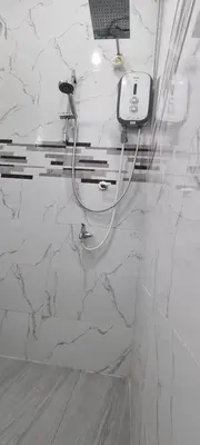 a white bathroom with a hair dryer on a wall at Tambun Hillview Cottage 1 in Tambun