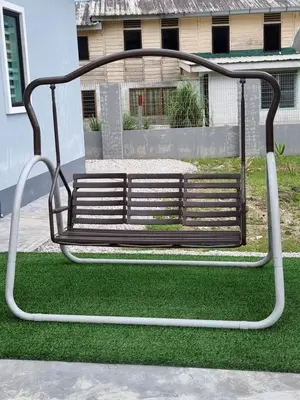 a metal bench sitting on the grass in front of a house at Tambun Hillview Cottage 1 in Tambun