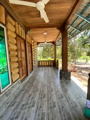 an open porch with wooden floors and a ceiling fan at HOMESTAY DUSUN ANA BALUN in Slim River