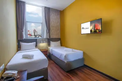 a hotel room with two beds and a flat screen tv at CitiVilla Hotel Penang in George Town