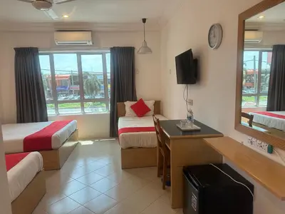 a room with two beds and a desk and a tv at V HOTEL in Teluk Intan