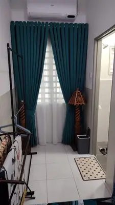 a room with blue curtains and a window at Mieda Rizqi Homestay in Kampong Melayu Changkat Larah