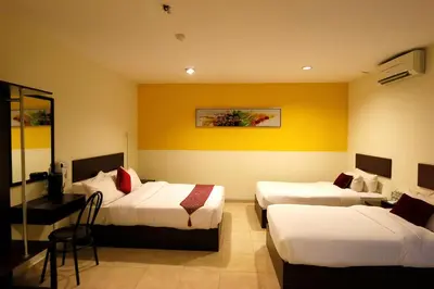a hotel room with two beds and a table and chairs at Golden Roof Hotel Falim Ipoh in Ipoh