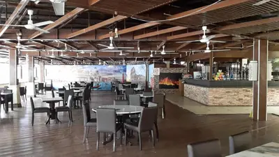 a restaurant with tables and chairs and a bar at D'Feringghi Hotel in Batu Ferringhi