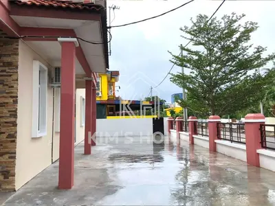 a building with red pillars on a rainy street at Kim’s Home - Homey At Your Stay in Nibung Tebal