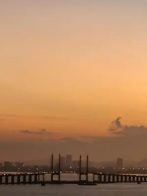 a bridge in the water with a sunset in the background at Infinite Seaview with Penang Bridge Suite with Sunrise up to 11 person in Bayan Lepas