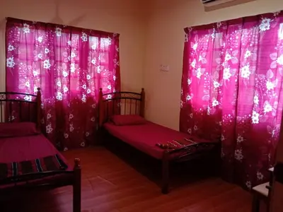 a bedroom with pink curtains and two twin beds at Sobey Laris Homestay CHIKU1 in Gua Musang