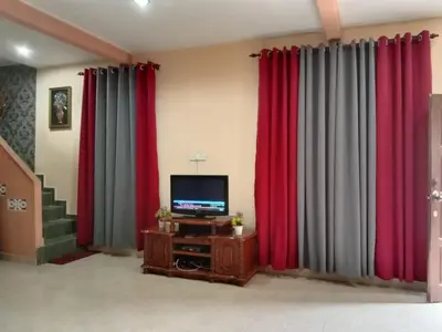 a living room with red and gray curtains and a television at Sobey Laris Homestay CHIKU1 in Gua Musang