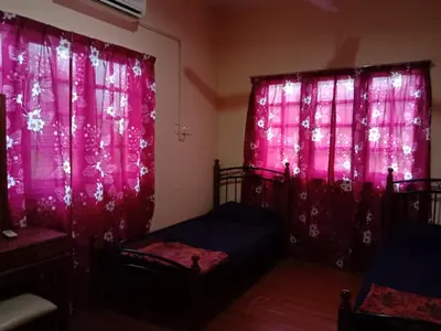 a bedroom with pink curtains and two beds in it at Sobey Laris Homestay CHIKU1 in Gua Musang