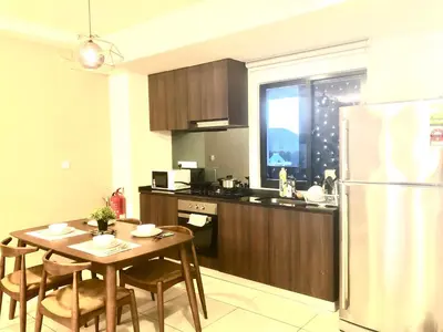 a kitchen with a table and a refrigerator at Seaview Water Purify Cozy Comfortable for Short & Long Stay in The Landmark by Katana in George Town