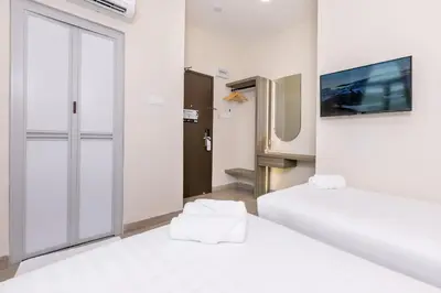 a room with two beds and a tv on the wall at E Hotel Kulim in Kulim