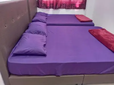 a bunk bed with purple sheets and a red pillow at Pangkor L29, Dream Island Homestay in Kampong Sungai Udang