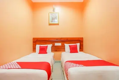 two beds in a room with orange walls at Bercam Times Inn Hotel in Ipoh