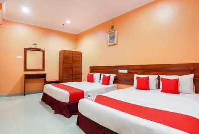 two beds in a hotel room with red and white pillows at Bercam Times Inn Hotel in Ipoh