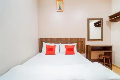 a bedroom with a white bed with red pillows at Hill Times Inn Hotel in Ipoh