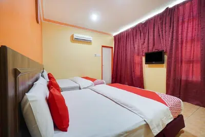 a bedroom with a large bed with red curtains at Hill Times Inn Hotel in Ipoh