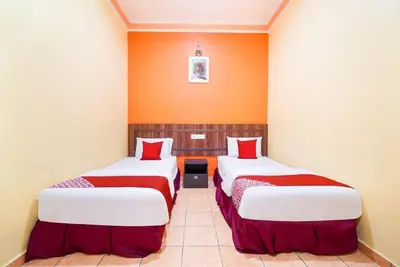 two beds in a room with orange walls at Hill Times Inn Hotel in Ipoh