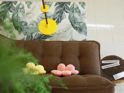 a brown couch with two pink flowers on it at Private Tree House - Cinema at CEO Bayan Lepas Penang in Bayan Lepas