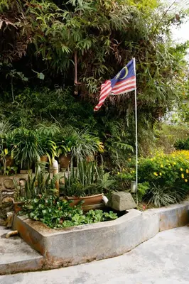 an american flag flying over a garden with a flag pole at Golden Lodge in Tanah Rata
