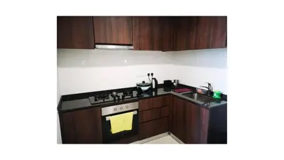a kitchen with wooden cabinets and a stove top oven at Tree Family Executive Suite 3 BR /8 PAX Gurney in Tanjong Tokong