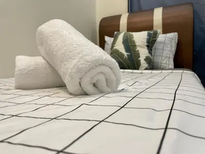 a roll of towels sitting on a bed at Zarahome in Tambun